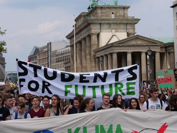 Gruppe von Schülern marschiert in Berlin mit einem bunt bemalten "Students for Future"-Schild.