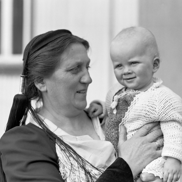 Eine Frau, die lachend ihr Baby hält, vor einem sanft unscharfen Hintergrund.