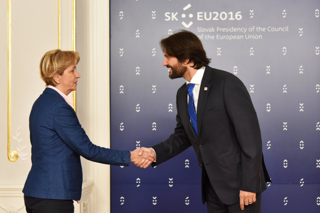 Bundeskanzlerin Angela Merkel und Bundeskanzler Joachim Gauck schütteln sich die Hände bei einem EU-Gipfeltreffen und lächeln freundlich.