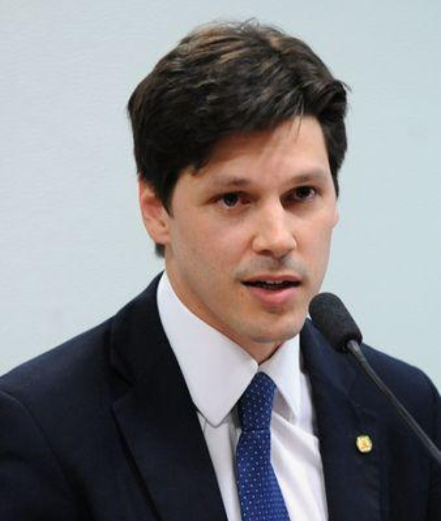 Ein Mann im Anzug und Krawatte spricht vor einer Wand in ein Mikrofon, wahrscheinlich zur Genehmigung eines Gesetzes durch die Regierung.