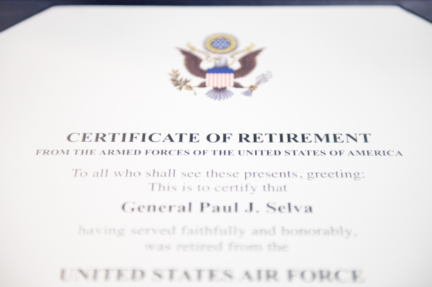 Rahmenurkunde der United States Air Force mit blauer Einfassung, zentralem Sternschild-Logo innerhalb eines Lorbeerkranzes und einer 'Retirement'-Banderole, alles in schwarzer Tinte gedruckt.