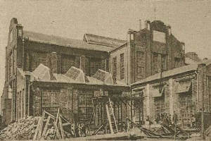 Schwarz-weiß-Fotografie der Sydney Central Railway Station im Bau, mit Holzmaterialien, einem Wagen und einem Himmel-Hintergrund, mit dem Stationsnamen am unteren Rand aufgedruckt.