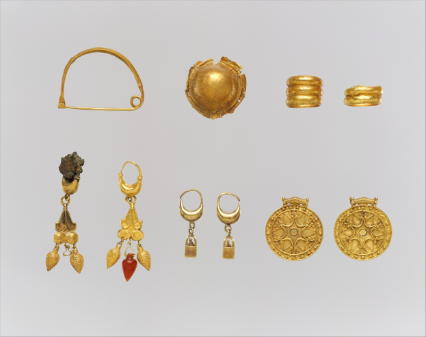Eine Sammlung von goldenen Ohrringen und Ringen, die auf einer weißen Oberfläche angeordnet sind und im Licht funkeln.