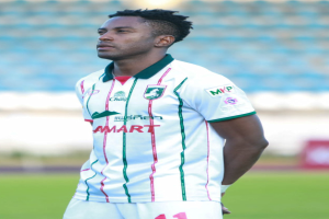 Der ghanaische Fußballspieler Emmanuel Adebayor steht auf einem Fussballfeld und trägt ein weisses und grünes T-Shirt und Shorts.