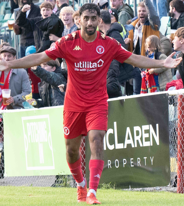 Ein Fussballspieler in rotem Trikot rennt auf einem Feld mit ausgebreiteten Armen, umgeben von Zuschauern, mit einem Banner im Hintergrund, das 'Middlesbrough FC v Swansea City - Sky Bet Championship' zeigt.