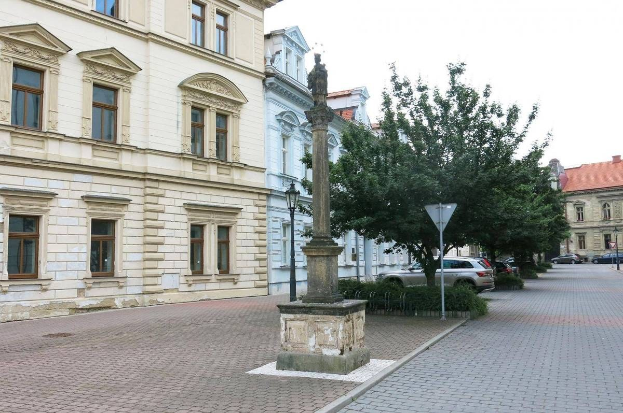 Schwarze und weiße Zeichnung der Statue des Heiligen Majestrat König Maximilian I. von Bayern in einem Stadtplatz mit Gebäuden, Bäumen, Menschen und Himmel im Hintergrund, mit Text unten.