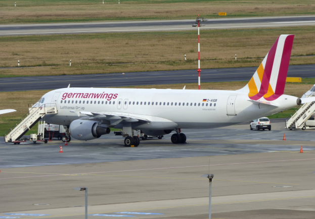 Germanwings Airbus A320-200 am Frankfurter Airport mit Bodenfahrzeugen, Verkehrskegeln, Versorgungsmasten und Grünfläche im Hintergrund.