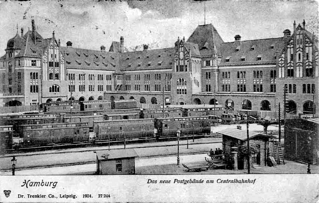 Eine Schwarz-Weiß-Postkarte, die ein altes Bahnhofsgebäude in Hamburg, Deutschland, zeigt, mit Gebäuden, Fenstern, Pfählen, Lampen, Zügen, Menschen und anderen Gegenständen im Vordergrund und Text am unteren Rand.