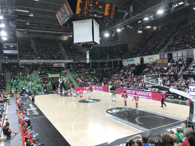 Basketballspiel in einer großen Arena mit Zuschauern, mit Teams Asvel und Galatasaray, wie auf den Werbetafeln zu sehen.