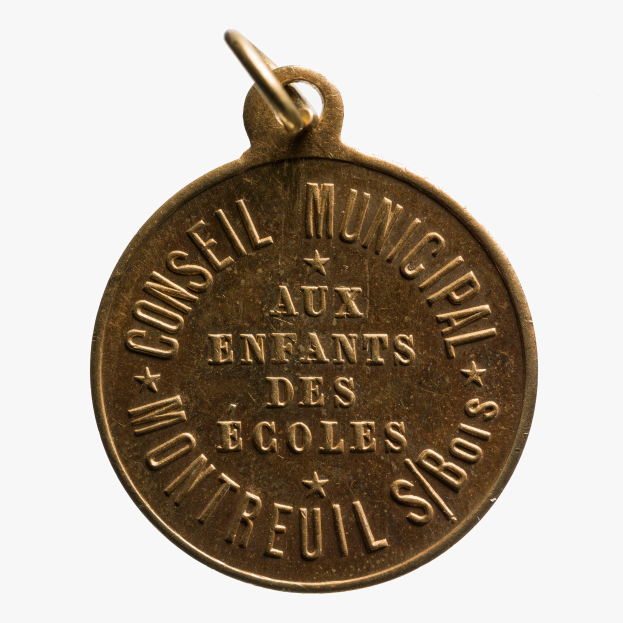 Eine Goldmedaille mit der Aufschrift "Conseil Municipal aux Enfants des Ecoles" auf einem weißen Hintergrund.