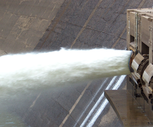 Wasserkraftwerk mit ausfließendem Wasser, das eine große Wolke bildet, und einer stromerzeugenden Maschine auf der rechten Seite.