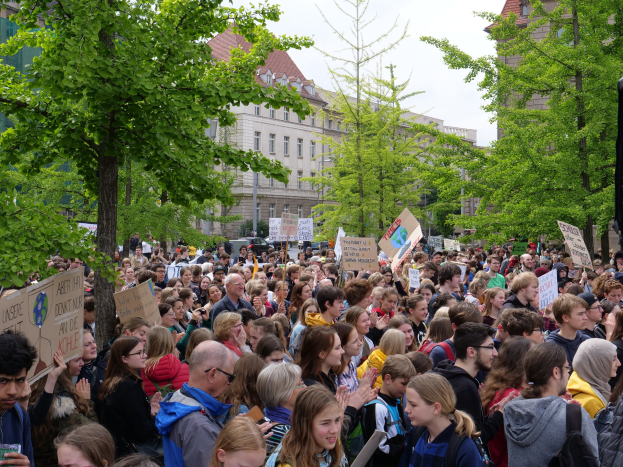 Eine große Menschenmenge protestiert vor einem Gebäude in Berlin und hält Schilder hoch.