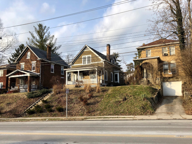 Reihe von Häusern mit Fenstern, Türen, Säulen, Geländern, Stufen, Pflanzen und einem Pfahl mit einer Tafel, die einen der teuersten Immobilien zum Verkauf in Detroit, Michigan darstellt.