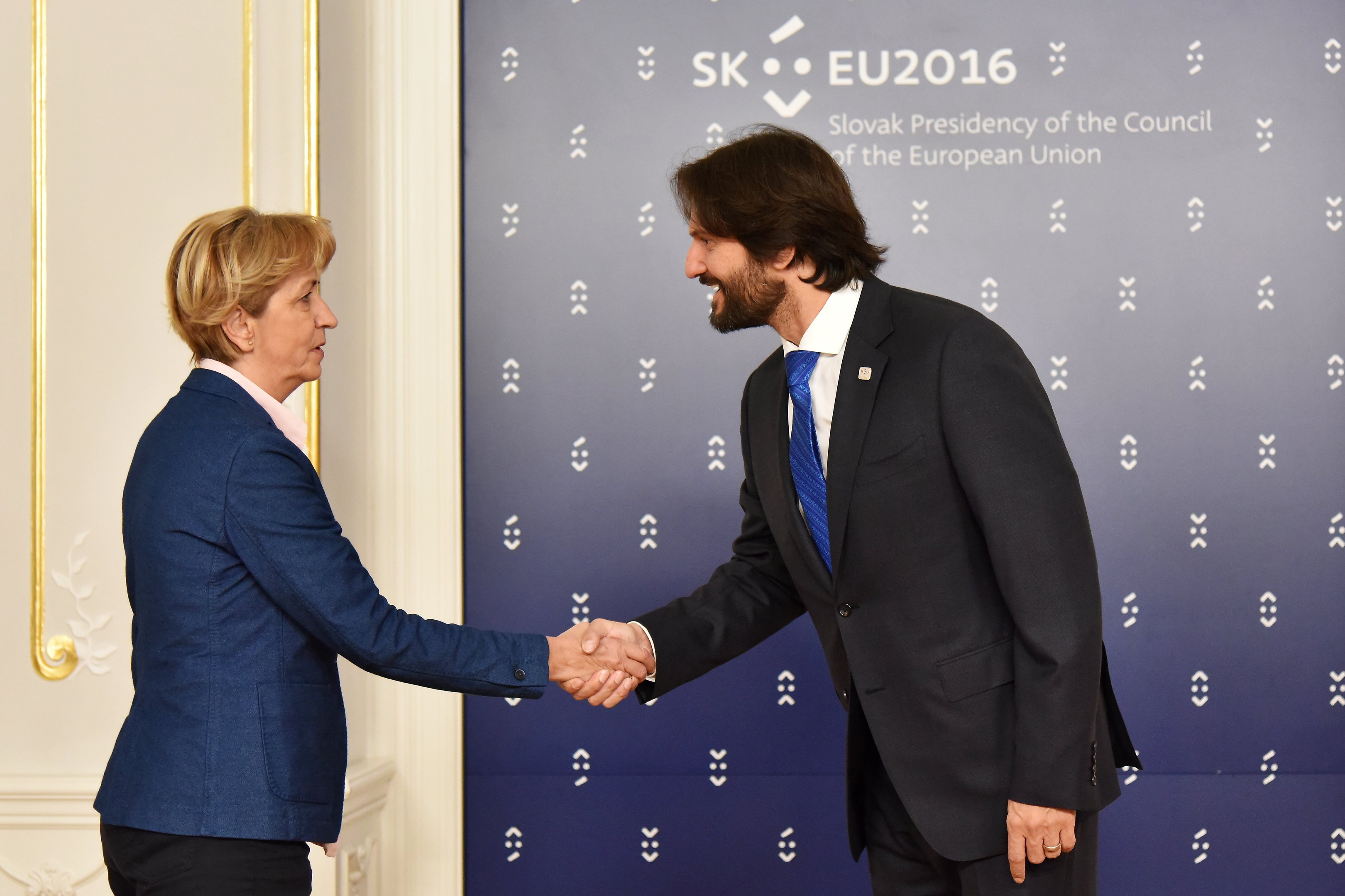 Bundeskanzlerin Angela Merkel und Bundeskanzler Joachim Gauck schütteln sich die Hände vor einem Banner mit der Aufschrift "EU-Gipfel", beide lächeln.