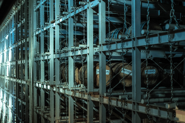 Ein großes Lager mit zahlreichen Fässern, die mit Metallstangen und Ketten verbunden und in einem ordentlichen Regalsystem angeordnet sind.