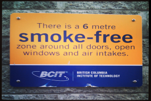 Ein Schild an der Wand mit der Aufschrift "Es besteht ein rauchfreier Bereich von 6 Metern um alle Türen, offenen Fenster und Luftansaugungen."