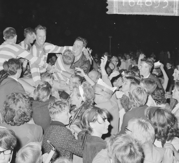 Ein Schwarz-Weiß-Foto einer Menge bei einem Konzert mit einer Gruppe von Menschen in der Mitte und Text in der oberen rechten Ecke.