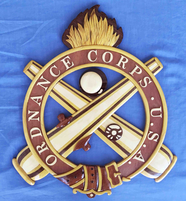 Holzschild mit "Ordnance Corps"-Text, zeigt ein geschnitztes weißes Stern auf marineblauem Hintergrund mit goldener Umrandung, montiert auf blauem Stoff in fettem schwarzem Schriftzug.